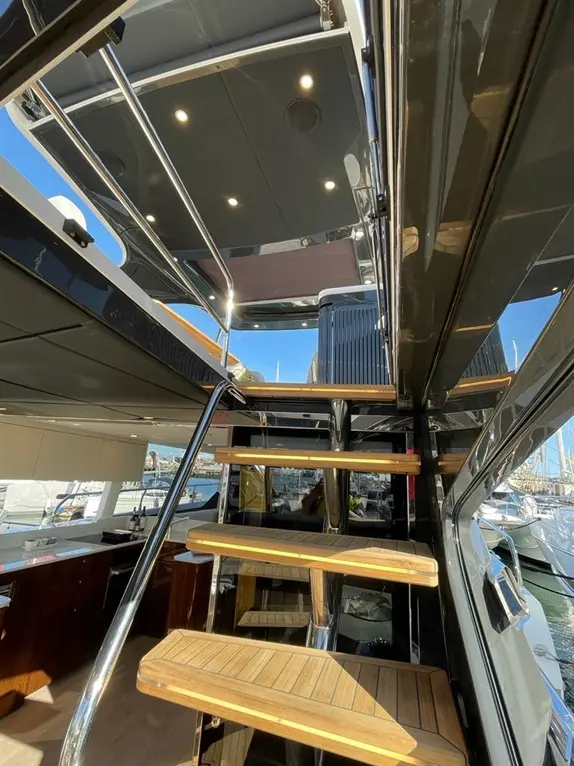 Interior view of a luxury yacht staircase, featuring wooden steps and stainless steel railings, leading to the upper deck.
